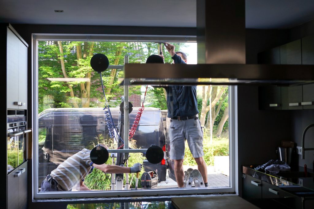 Window installers removing old, inefficient windows from a home during home improvement project.